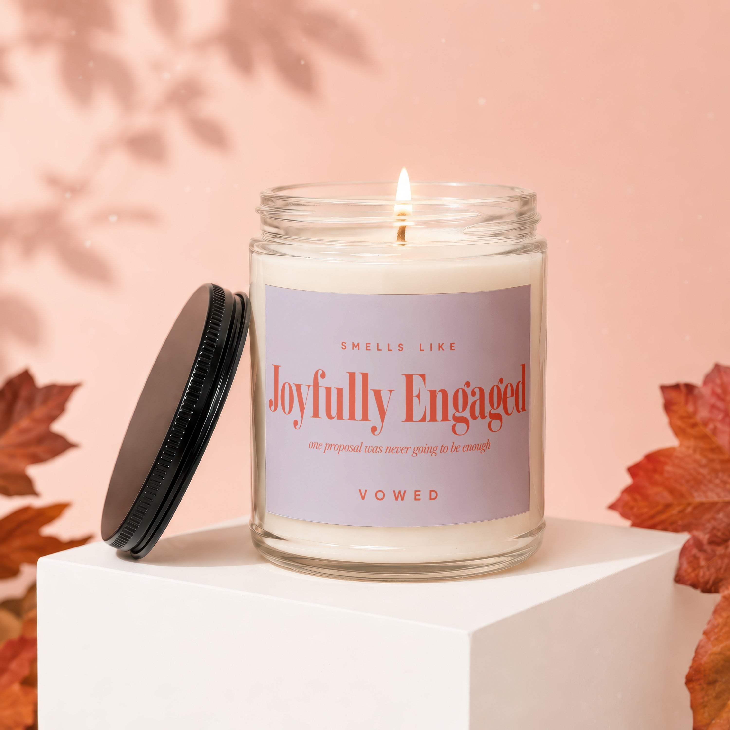 Candle with "Joyfully Engaged" and "Vowed" text, lit flame, and black lid.