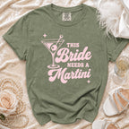 Green t-shirt with pink text reading "This Bride Needs A Martini" and a martini glass graphic.
