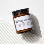 Brown glass candle with label reading "wedding planner" and VOWED logo.