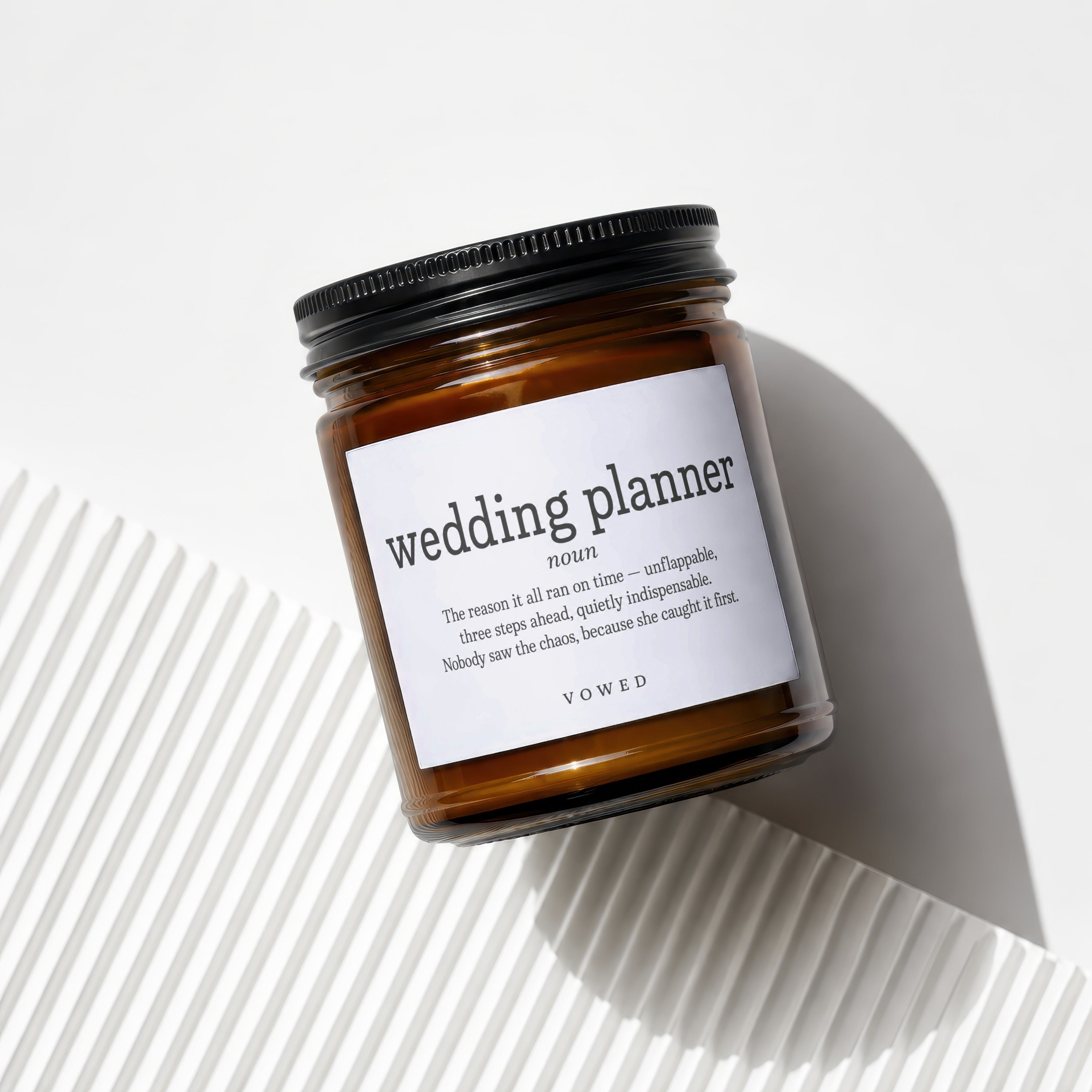 Brown glass candle with label reading "wedding planner" and VOWED logo.