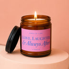 Lit candle in amber jar with pink label reading "SMELLS LIKE LOVE, LAUGHTER & Always After VOWED".