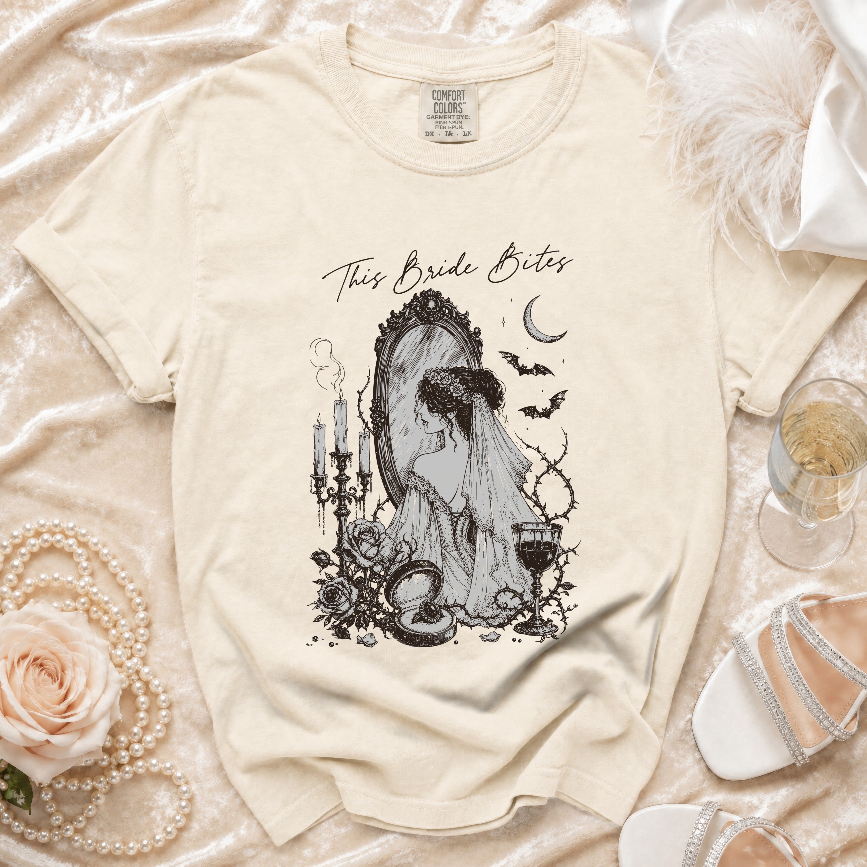 Cream t-shirt with "This Bride Bites" graphic of a bride at a mirror.