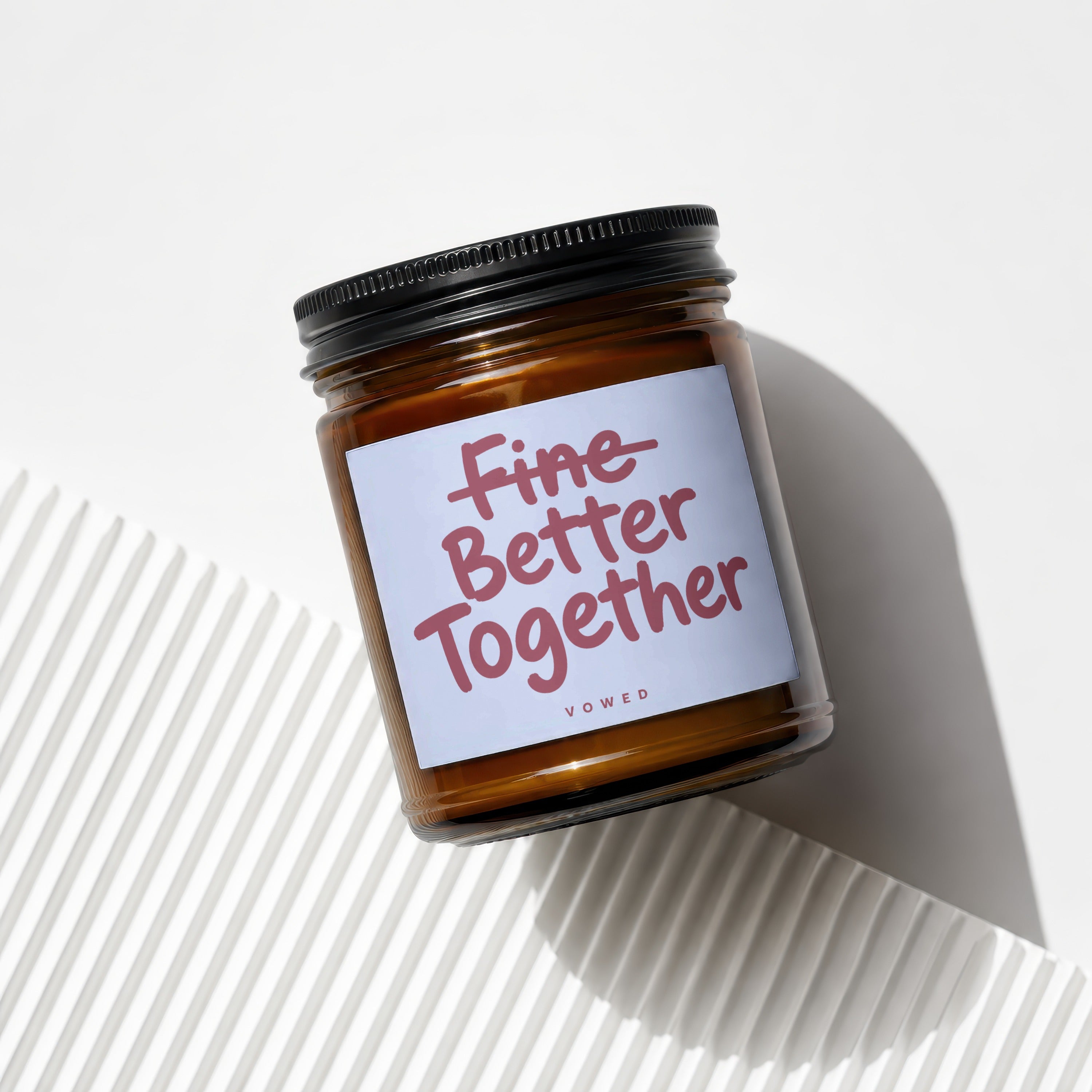 Amber candle jar with black lid and label reading "Fine Better Together".