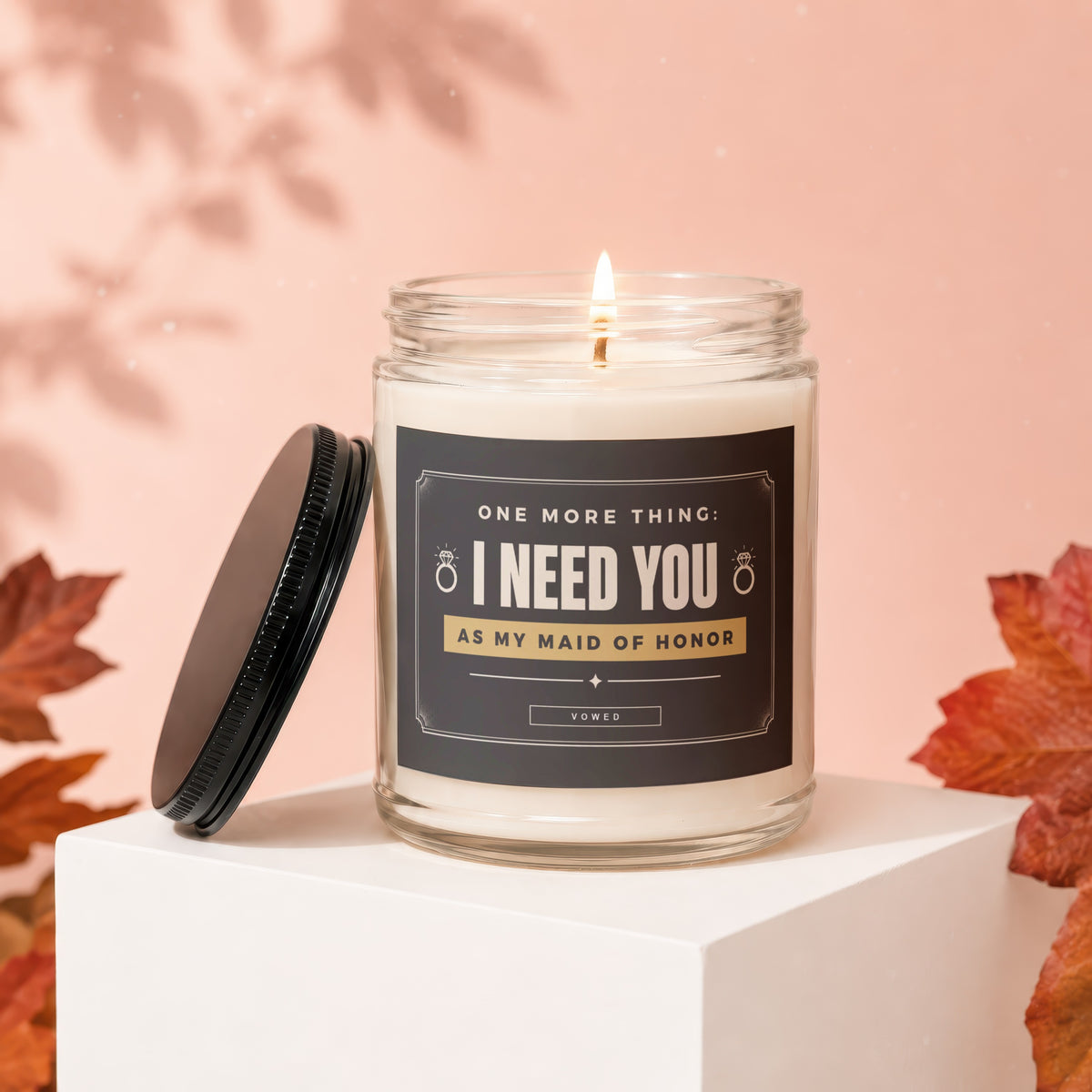 Glass candle with lit wick and label reading "I Need You As My Maid Of Honor".