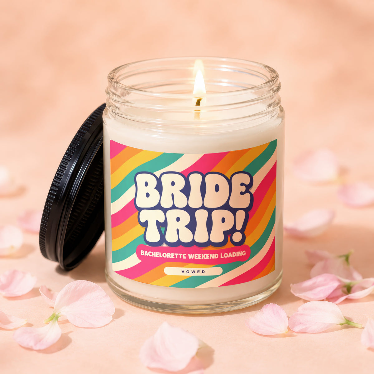 Lit candle with "BRIDE TRIP! BACHELORETTE WEEKEND LOADING" text on colorful label.