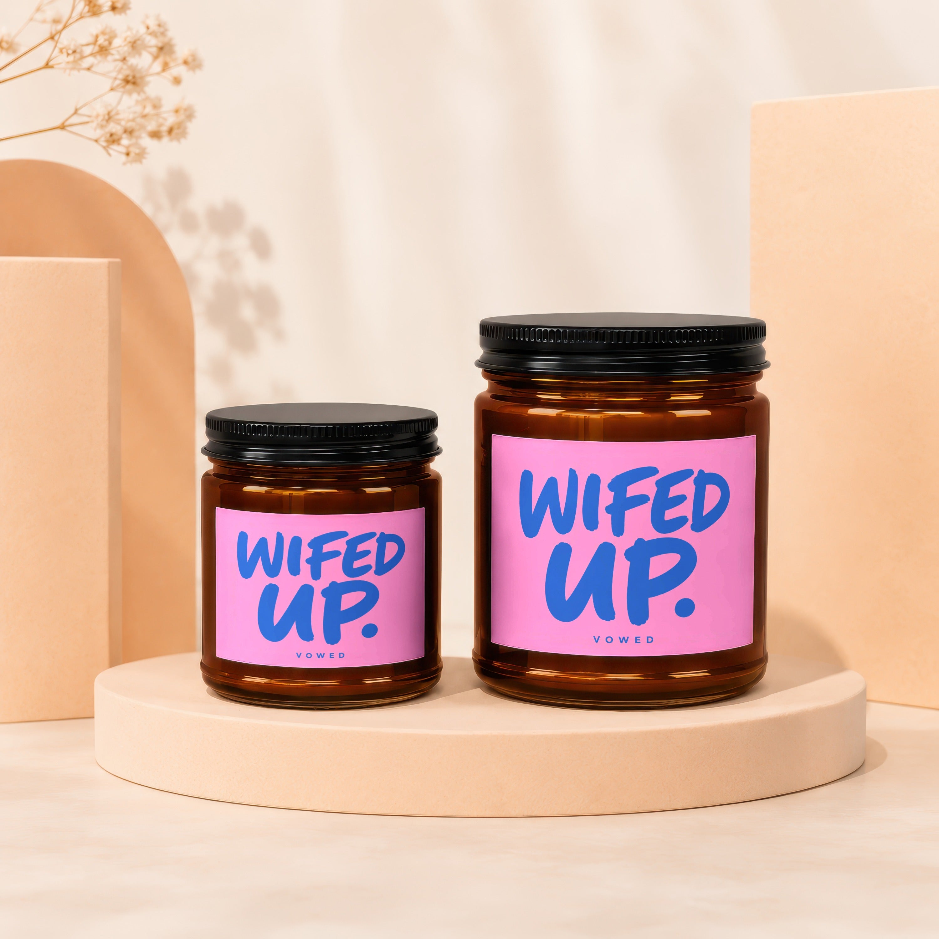 Two amber candles with pink labels that read "WIFED UP." and "VOWED"