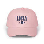 Light pink baseball cap embroidered with dark blue text reading LUCKY and a four-leaf clover.
