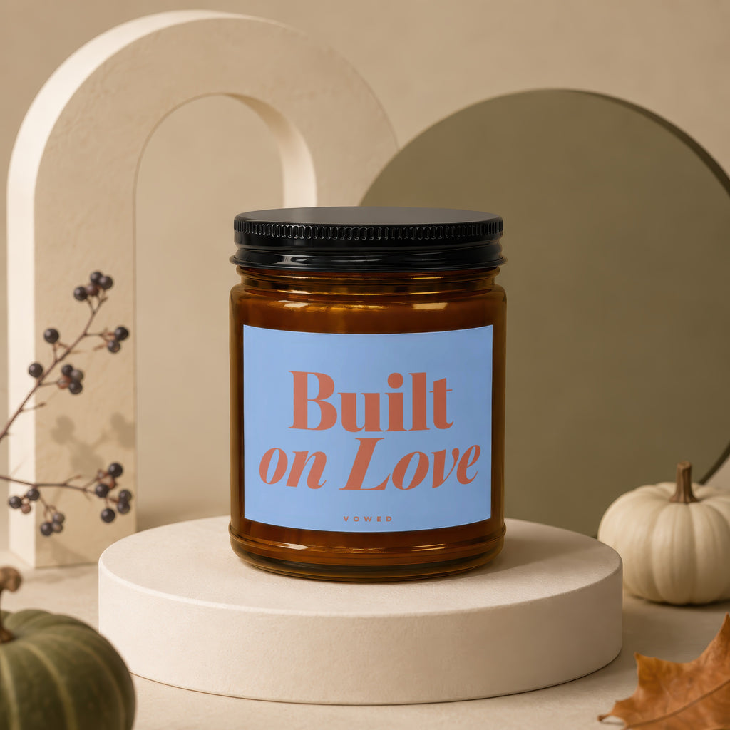 Amber candle with label "Built on Love" on a pedestal with decorative elements.
