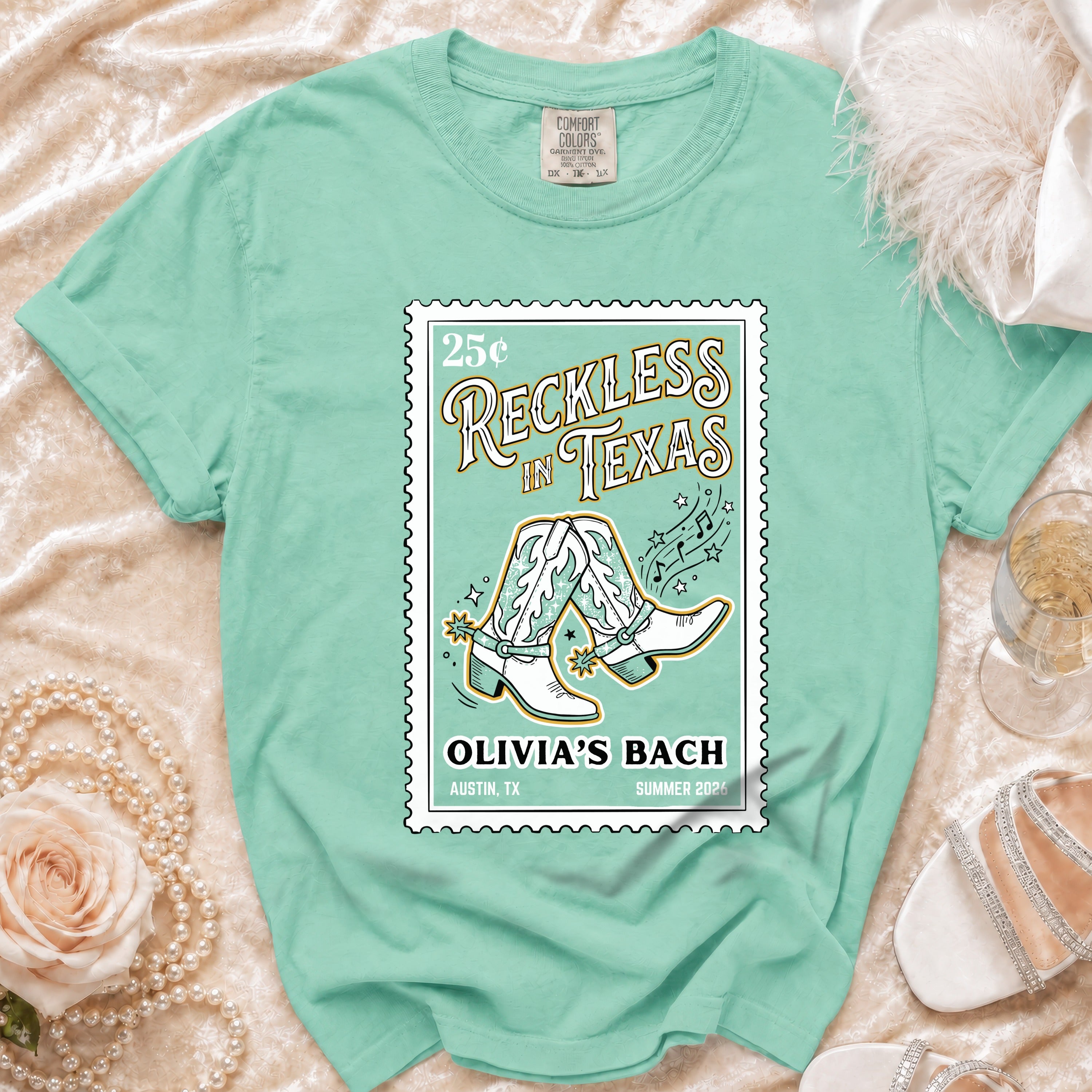 Mint green t-shirt with "Reckless in Texas" and cowboy boots graphic.
