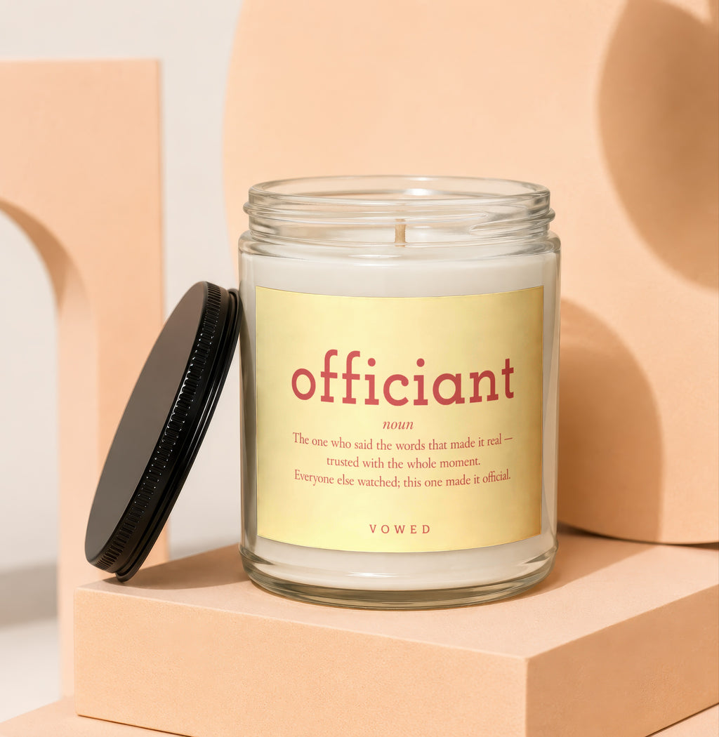 Candle with yellow label text "officiant noun..." and brand "VOWED".