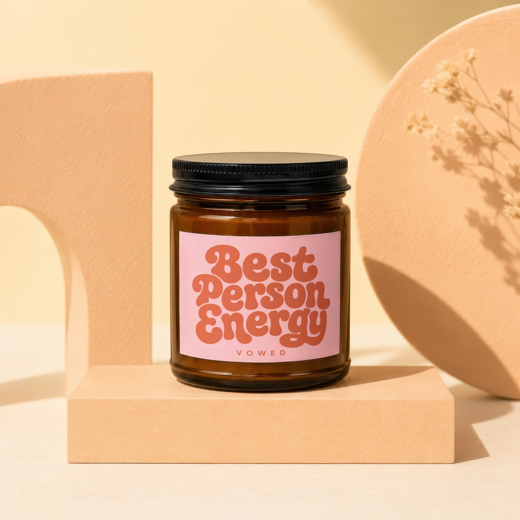 Amber candle with black lid and pink label reading "Best Person Energy VOWED."