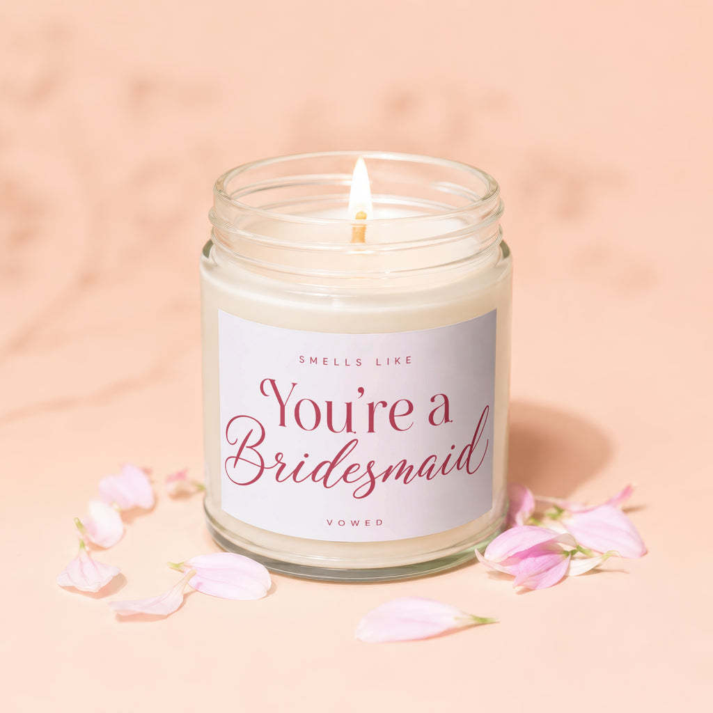 Glass candle with "You're a Bridesmaid" text, surrounded by pink petals.