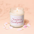 Glass candle with "You're a Bridesmaid" text, surrounded by pink petals.