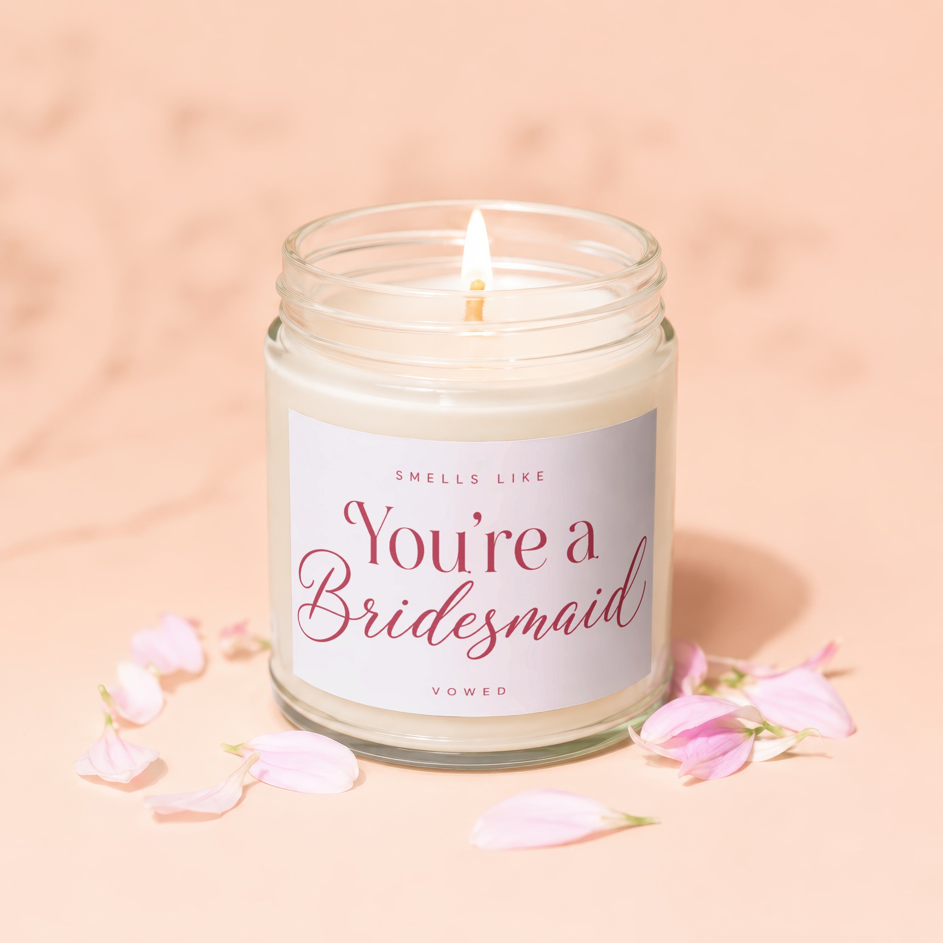 Glass candle with "You're a Bridesmaid" text, surrounded by pink petals.