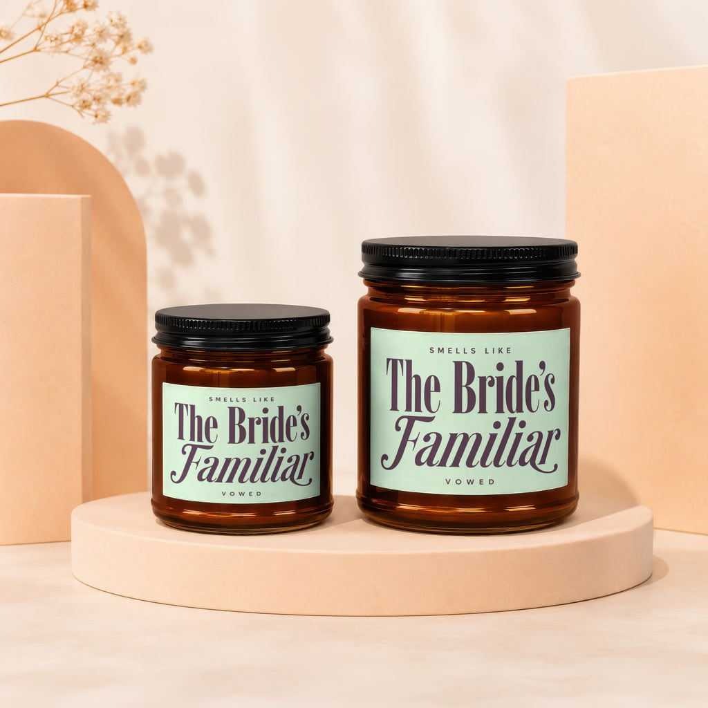 Two amber glass candles with black lids, labeled "The Bride's Familiar."
