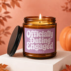 Amber jar candle with a lit wick, label reads "Officially Dating Engaged VOWED".