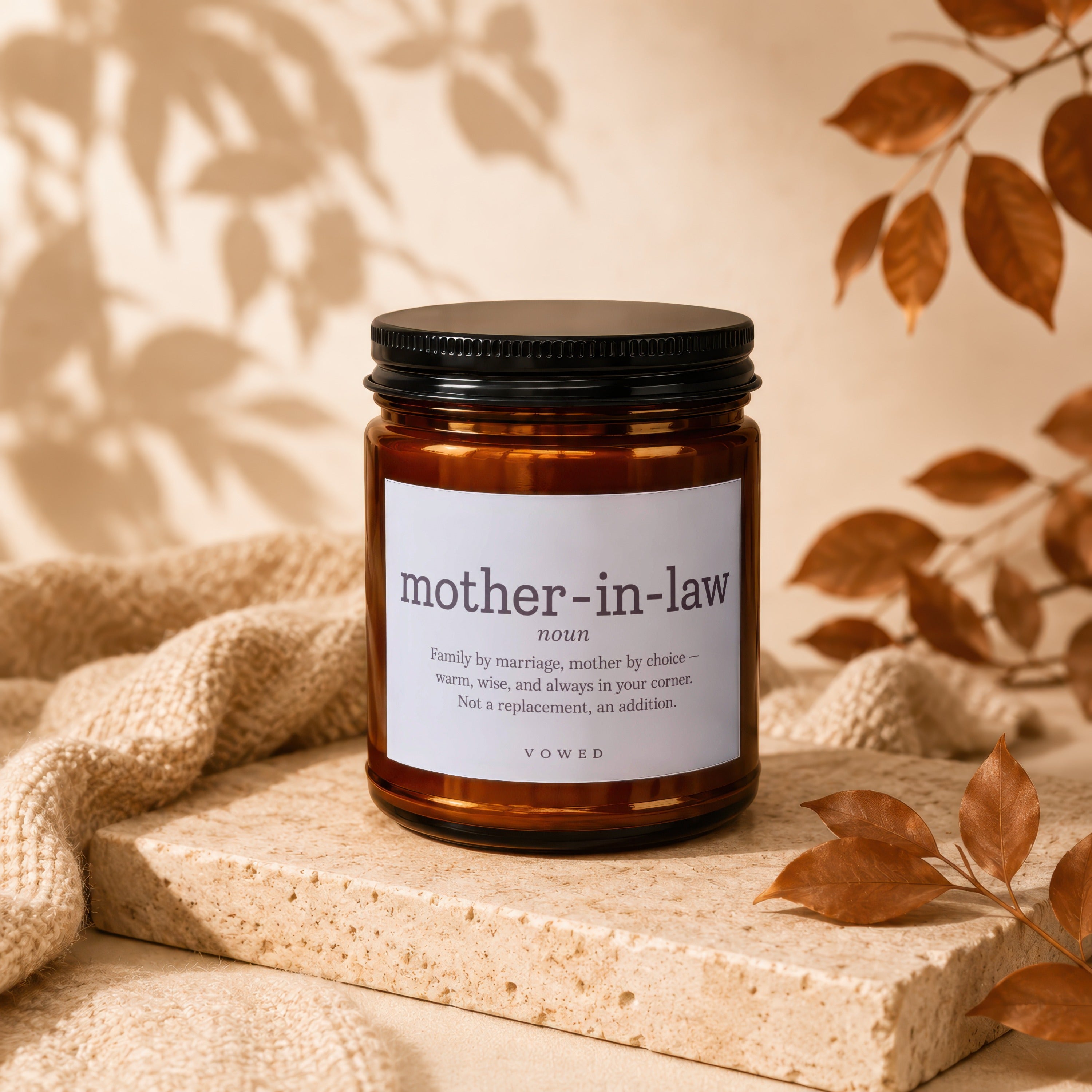 Amber jar candle with "mother-in-law" definition label, on stone.