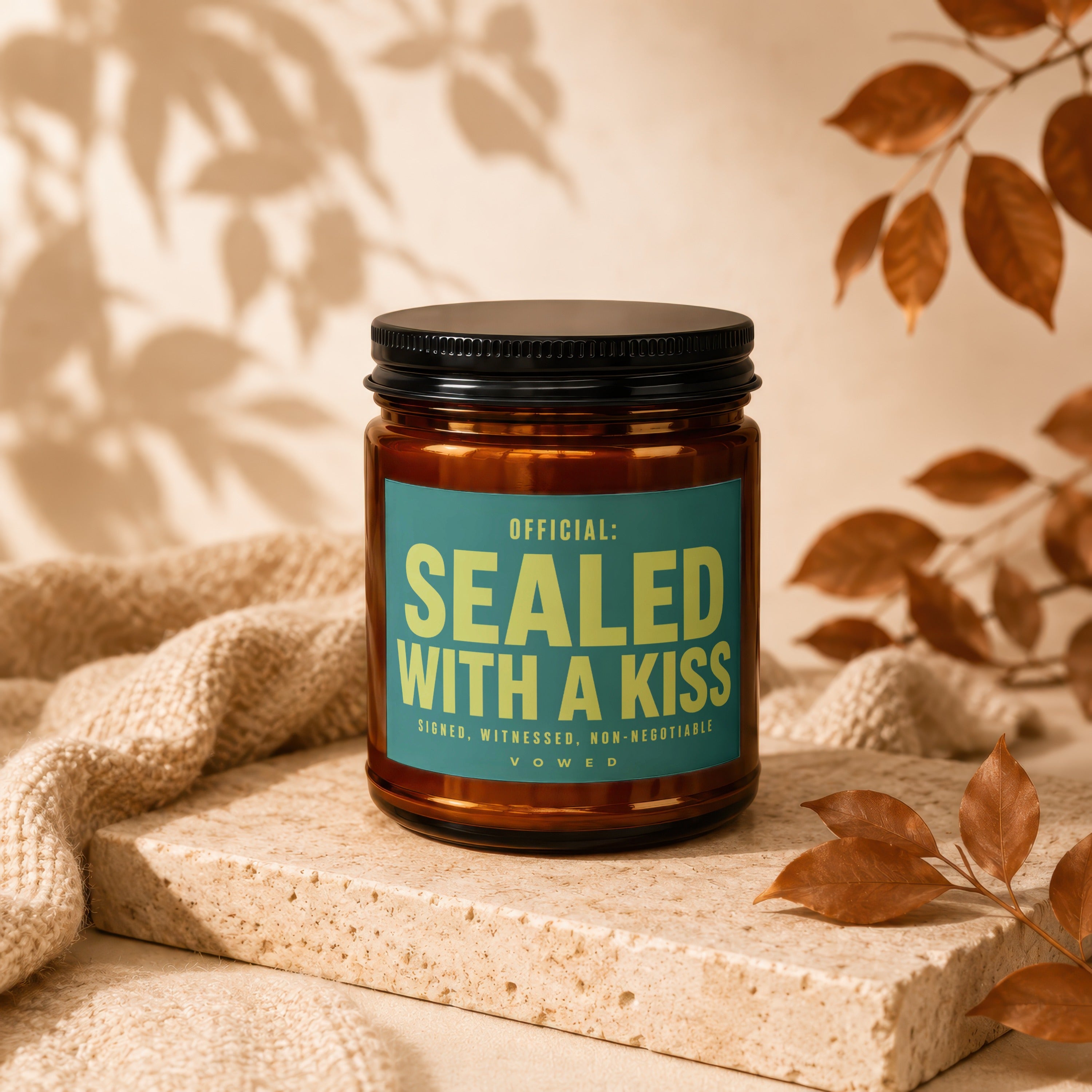 Amber jar candle with teal label reading "OFFICIAL: SEALED WITH A KISS"