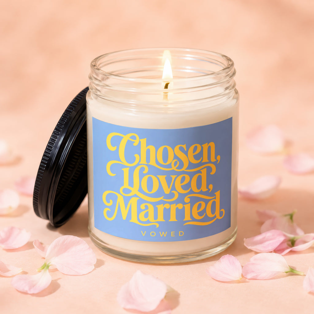 Lit candle with "Chosen, Loved, Married, Vowed" text on a blue label.