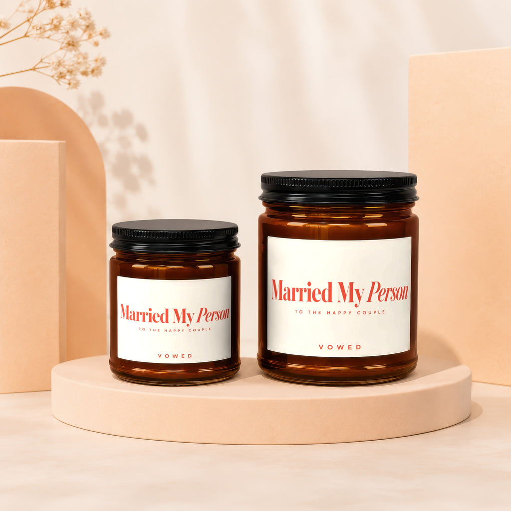 Two amber glass candles with white labels reading "Married My Person" and "Vowed".