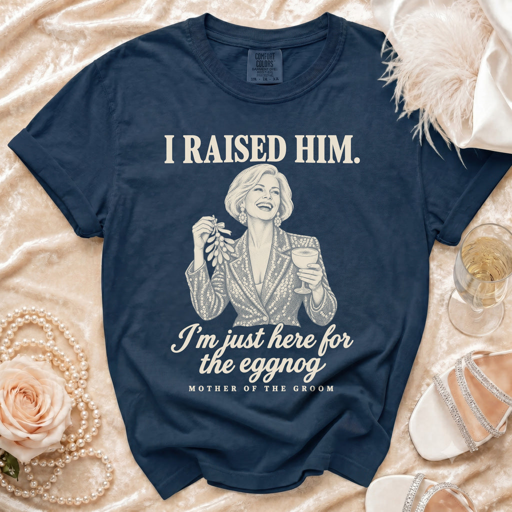 A dark blue t-shirt printed with the text I RAISED HIM and I'm just here for the eggnog.