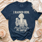 A dark blue t-shirt printed with the text I RAISED HIM and I'm just here for the eggnog.
