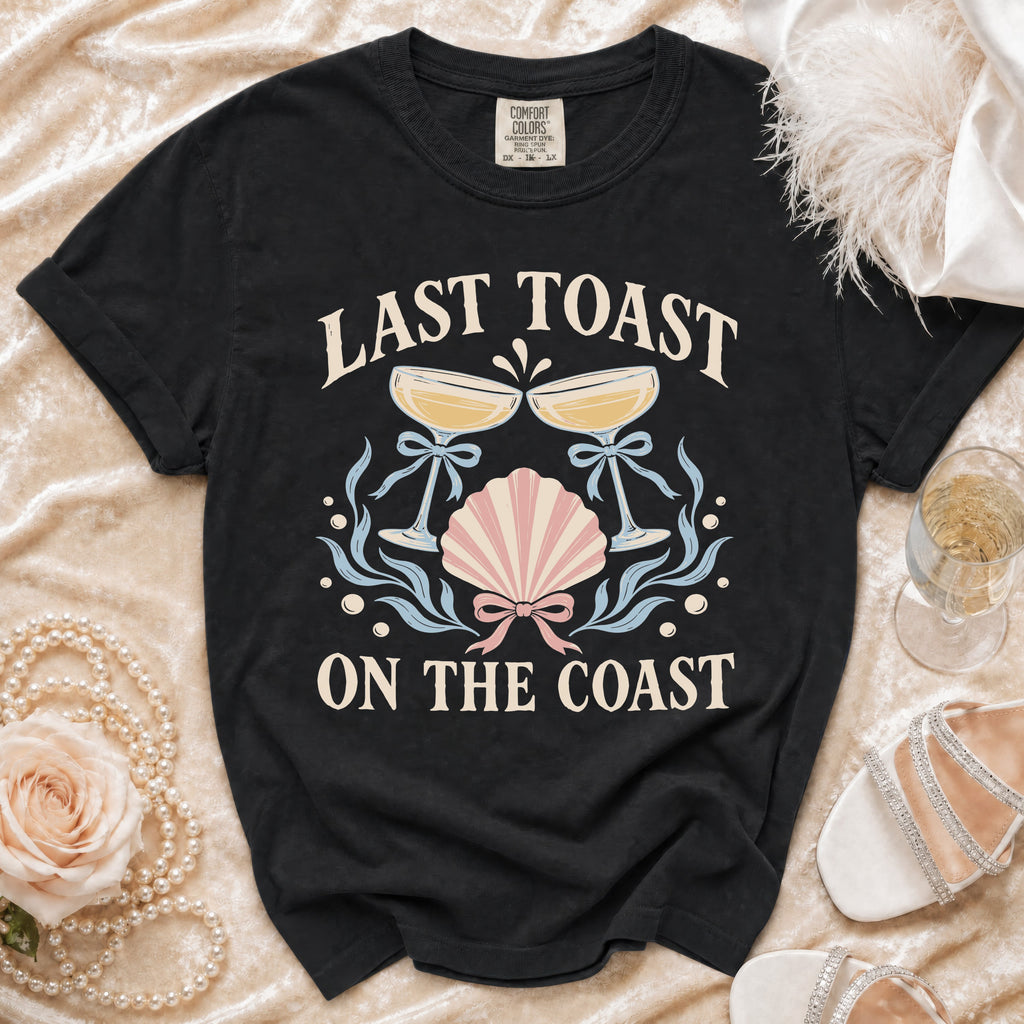Black t-shirt with "Last Toast On The Coast" text and nautical graphics.