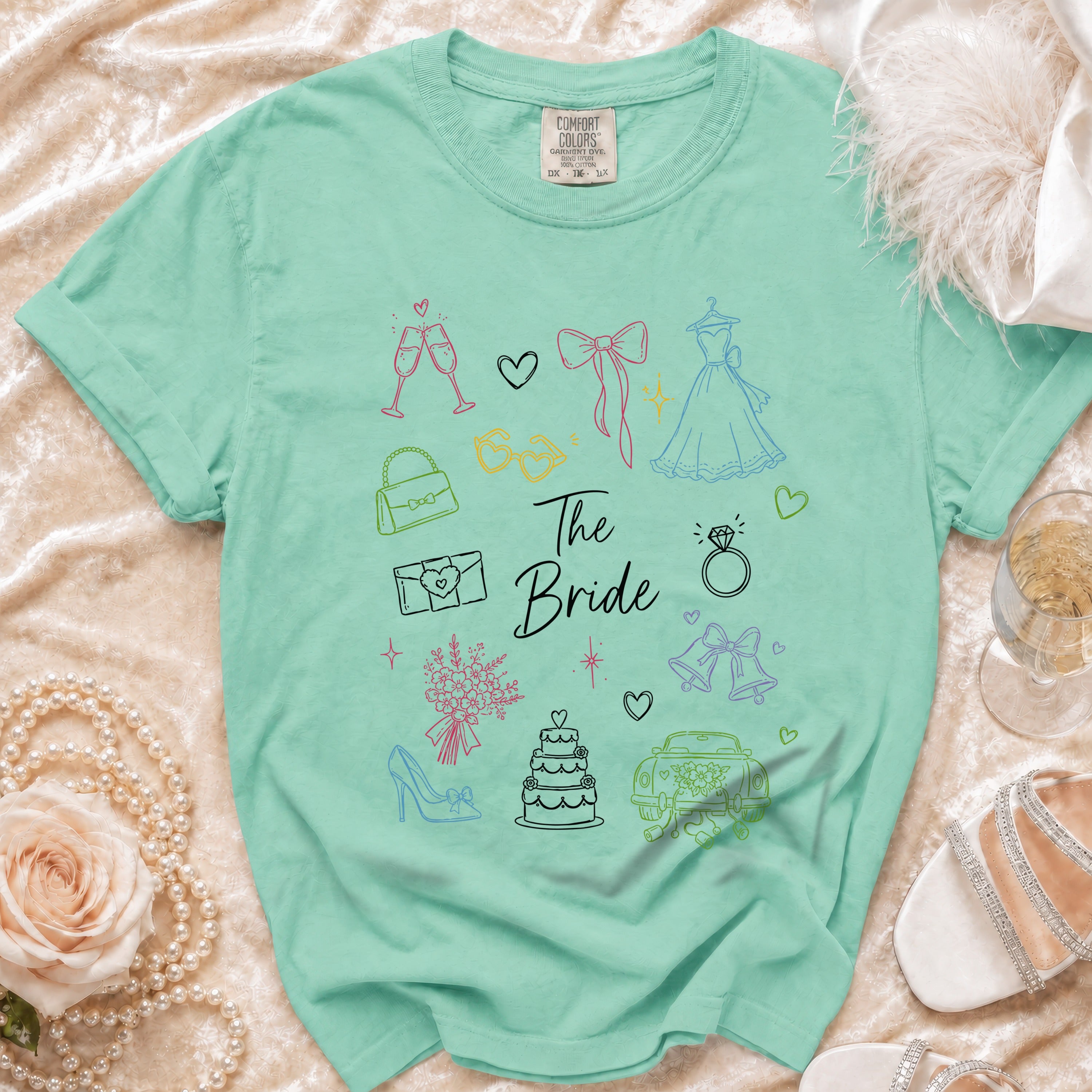 Mint green t-shirt with "The Bride" and wedding icons in colorful sketch style.