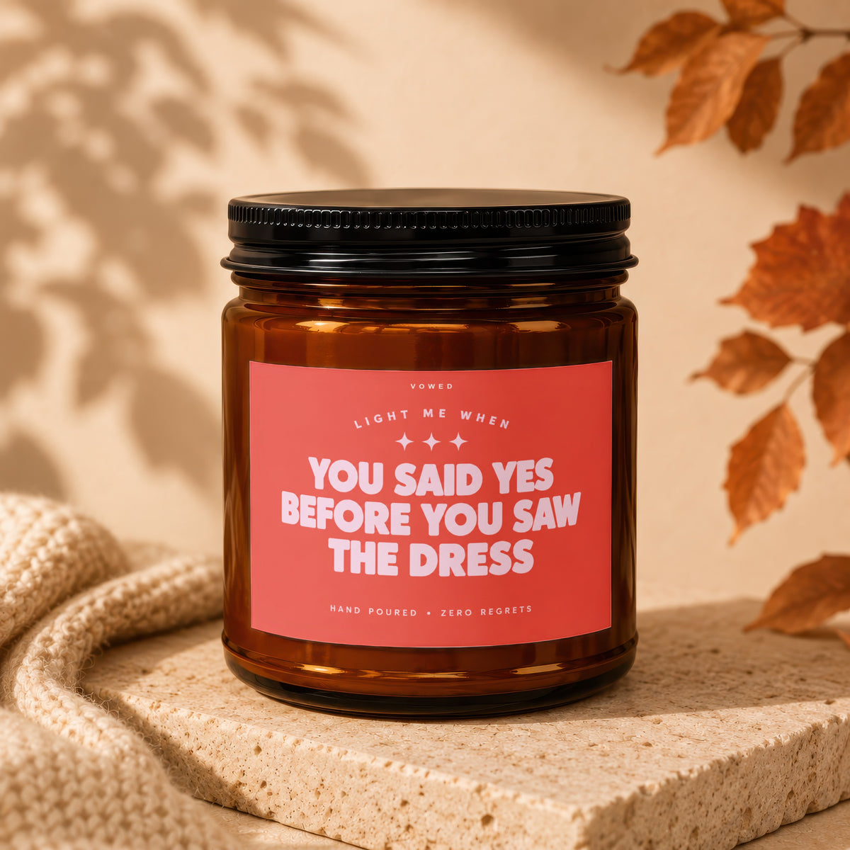Amber glass candle with red label reading "Light me when you said yes before you saw the dress."