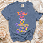 Blue t-shirt with text "I Run On Champagne And Chaos" and graphics.