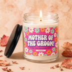 Glass candle with lit wick, featuring a "Mother of the Groom" label with flowers.