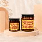 Two amber glass candles display yellow labels with "Officially Taken Engaged" text.