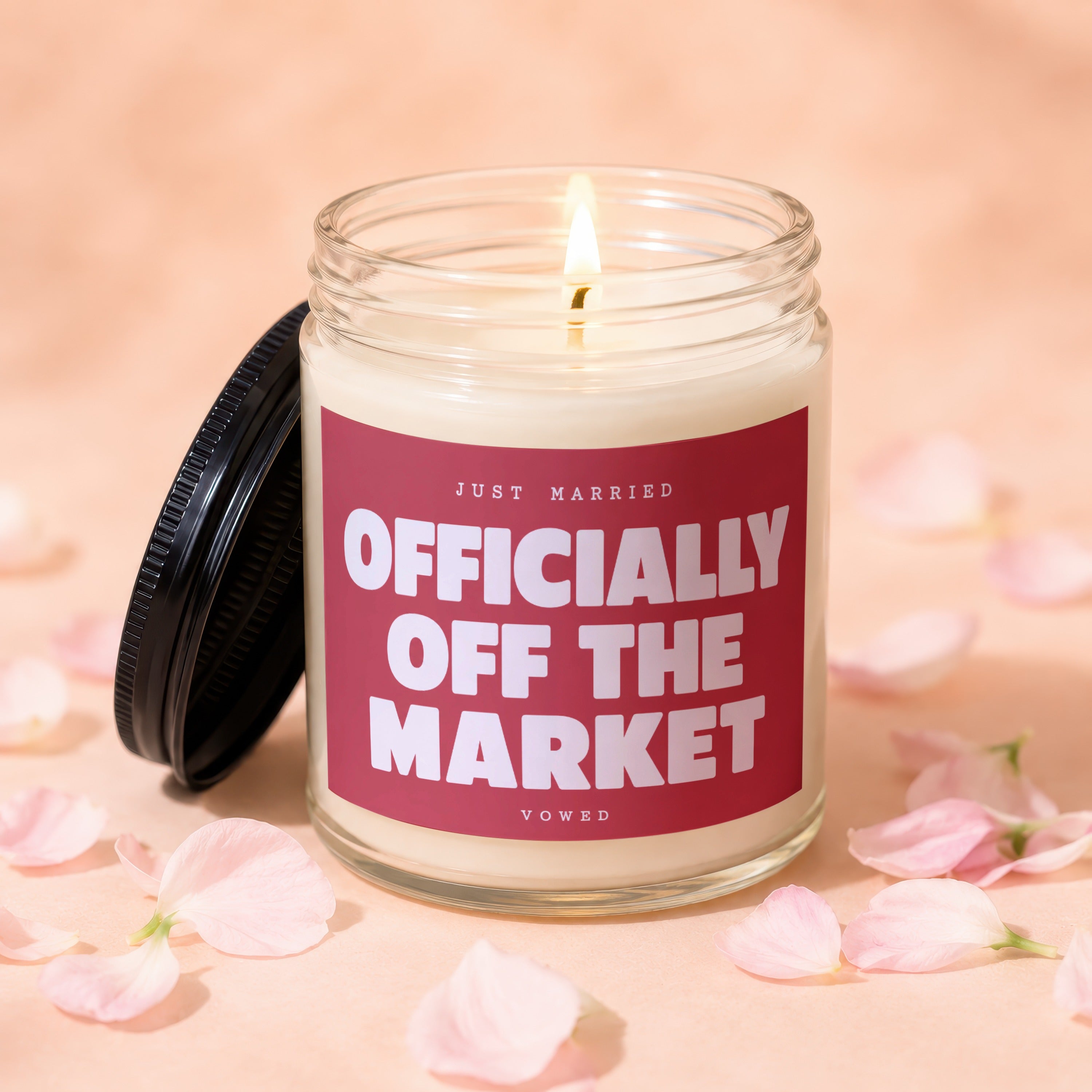 Glass candle with flame, "Officially Off The Market" text, and light pink petals.