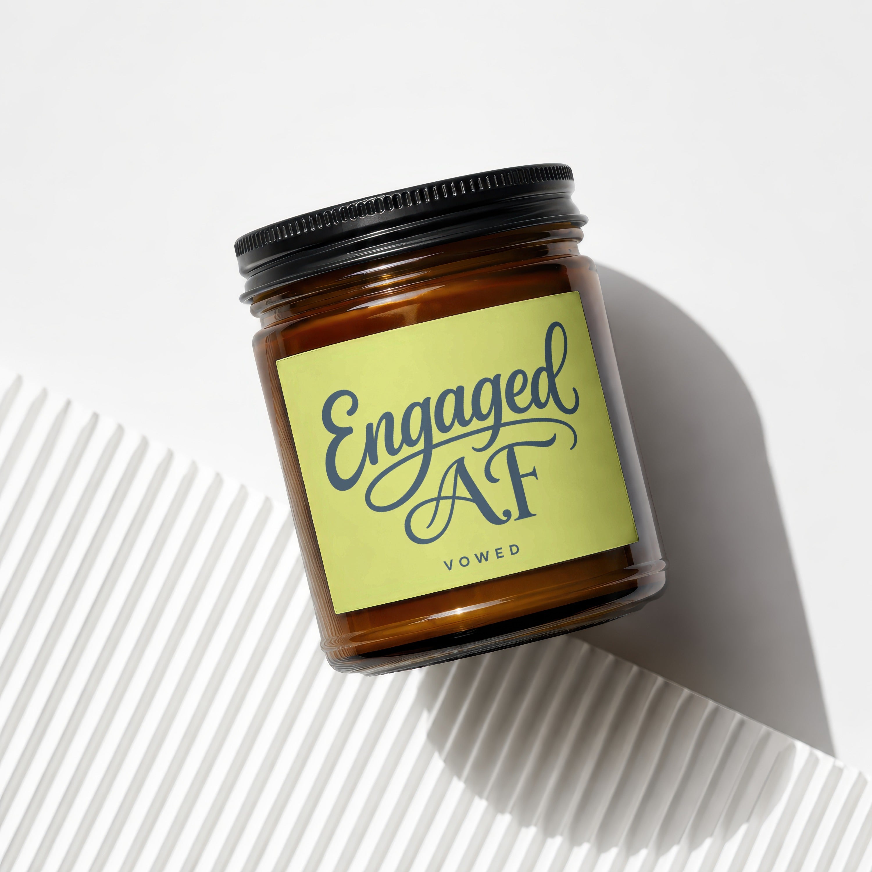 Amber candle with black lid, yellow label reads "Engaged AF VOWED".