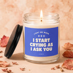 Glass candle with lit wick and blue label reading "Light me when I start crying as I ask you".