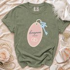 Olive green t-shirt with "honeymoon suite" text on a pink tag, next to a key.