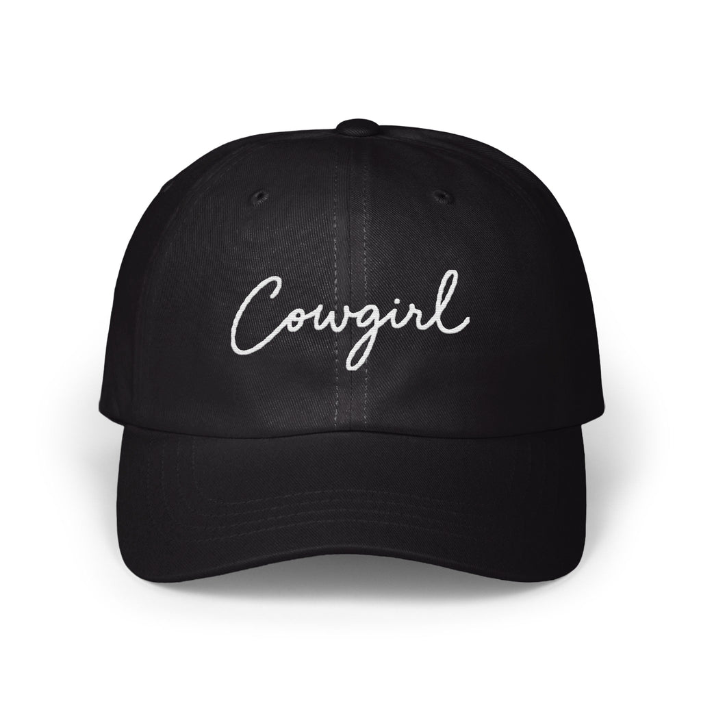 A black dad hat features the word Cowgirl embroidered in white cursive script across the front panels.