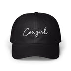 A black dad hat features the word Cowgirl embroidered in white cursive script across the front panels.