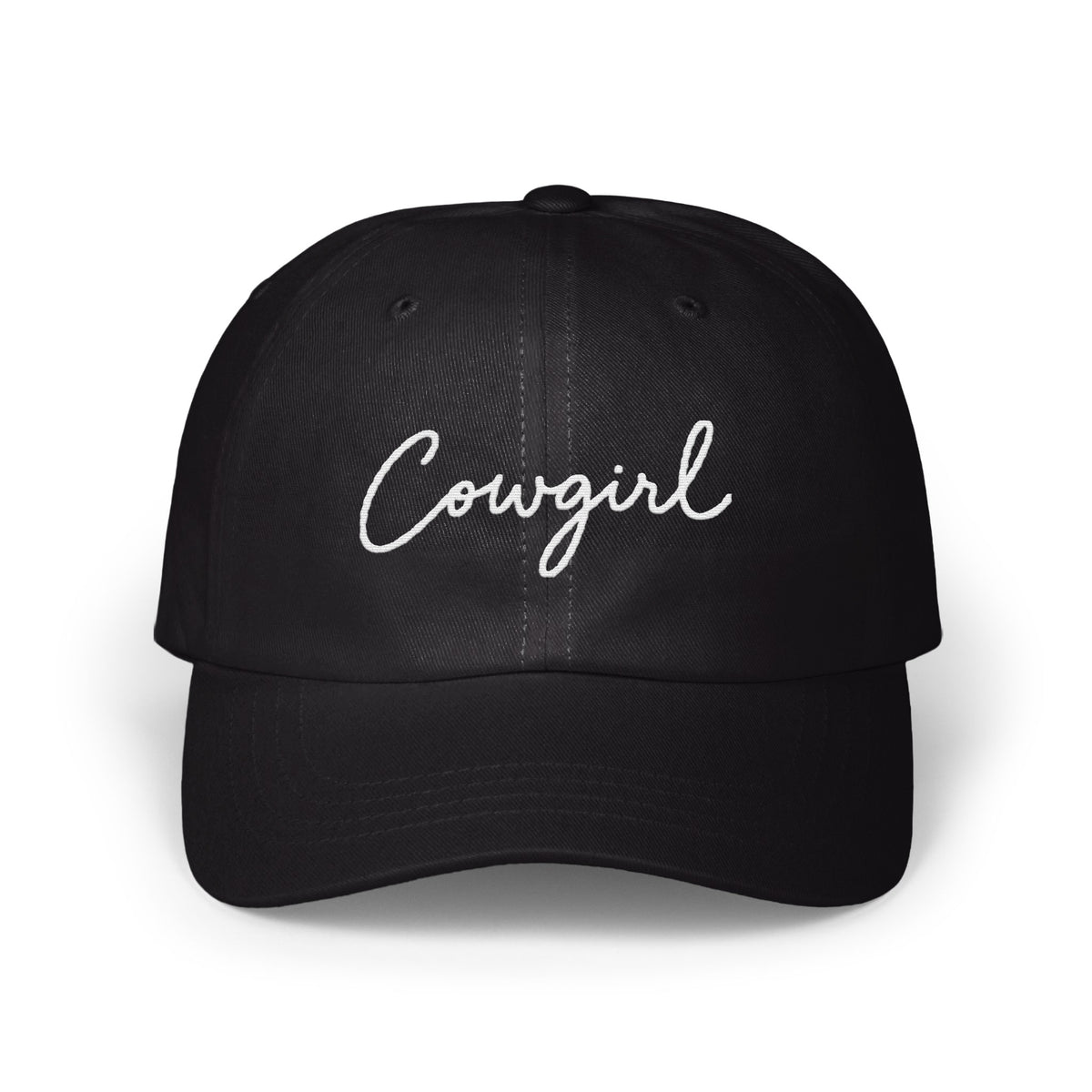 A black dad hat features the word Cowgirl embroidered in white cursive script across the front panels.