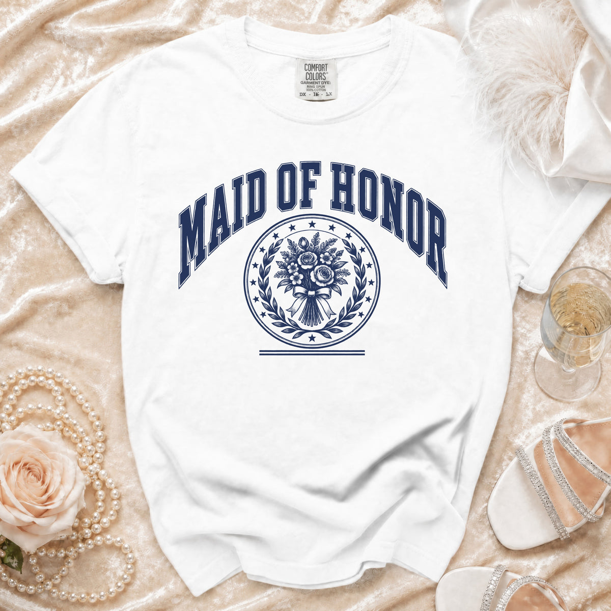 White t-shirt with "Maid of Honor" text and floral wreath emblem.