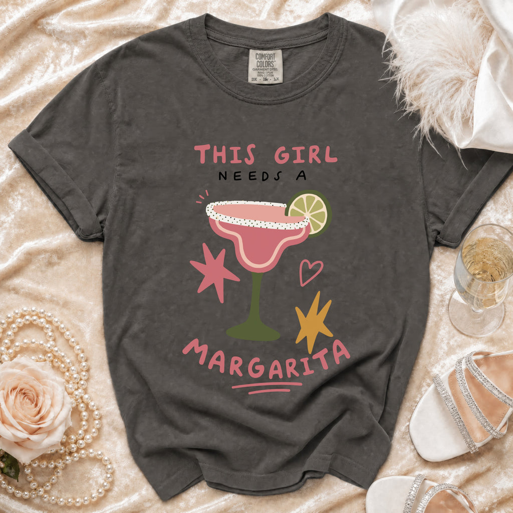 Dark grey Comfort Colors t-shirt with "This Girl Needs a Margarita" graphic and margarita illustration.