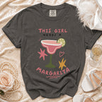 Dark grey Comfort Colors t-shirt with "This Girl Needs a Margarita" graphic and margarita illustration.