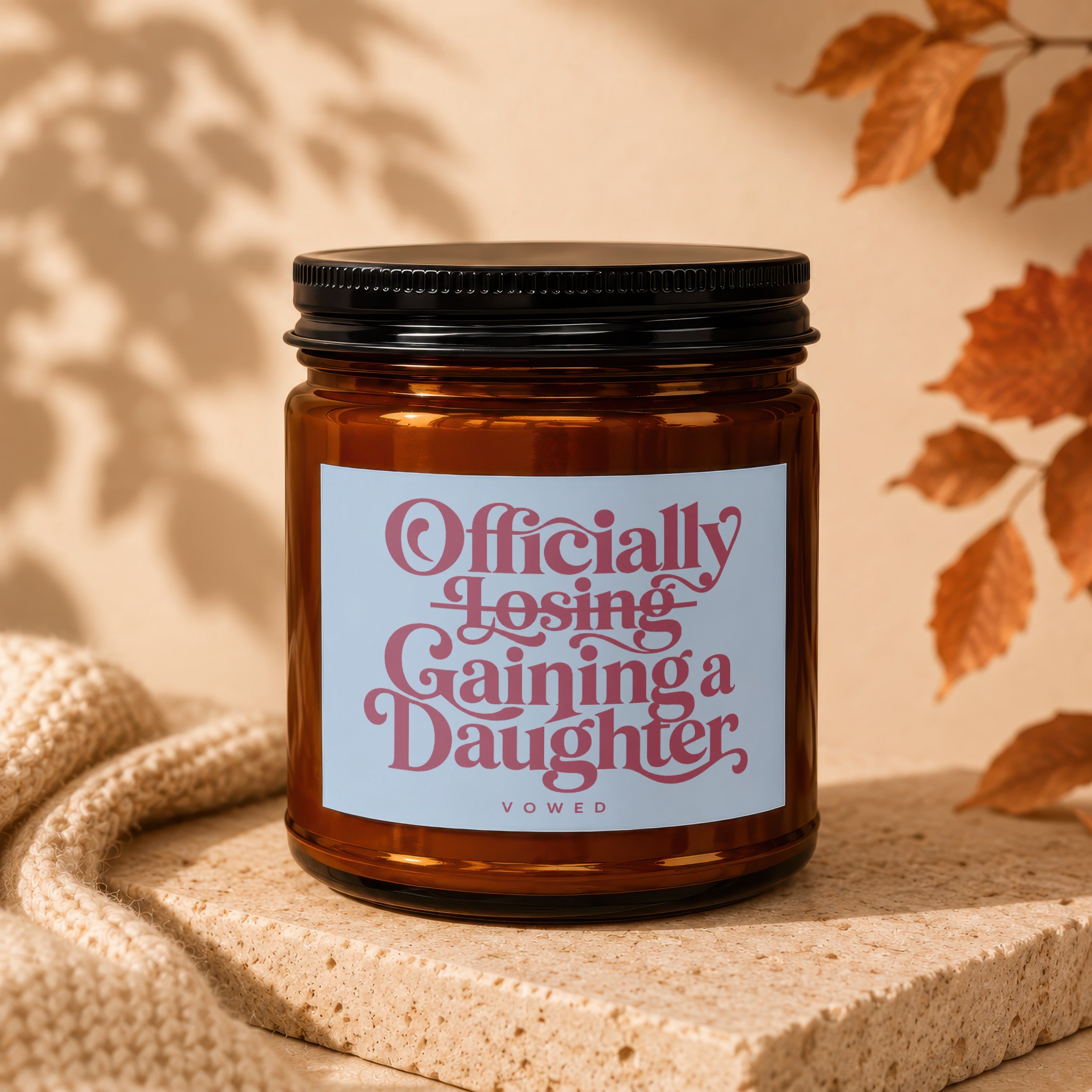 Amber candle with label reading "Officially Losing Gaining a Daughter, VOWED".