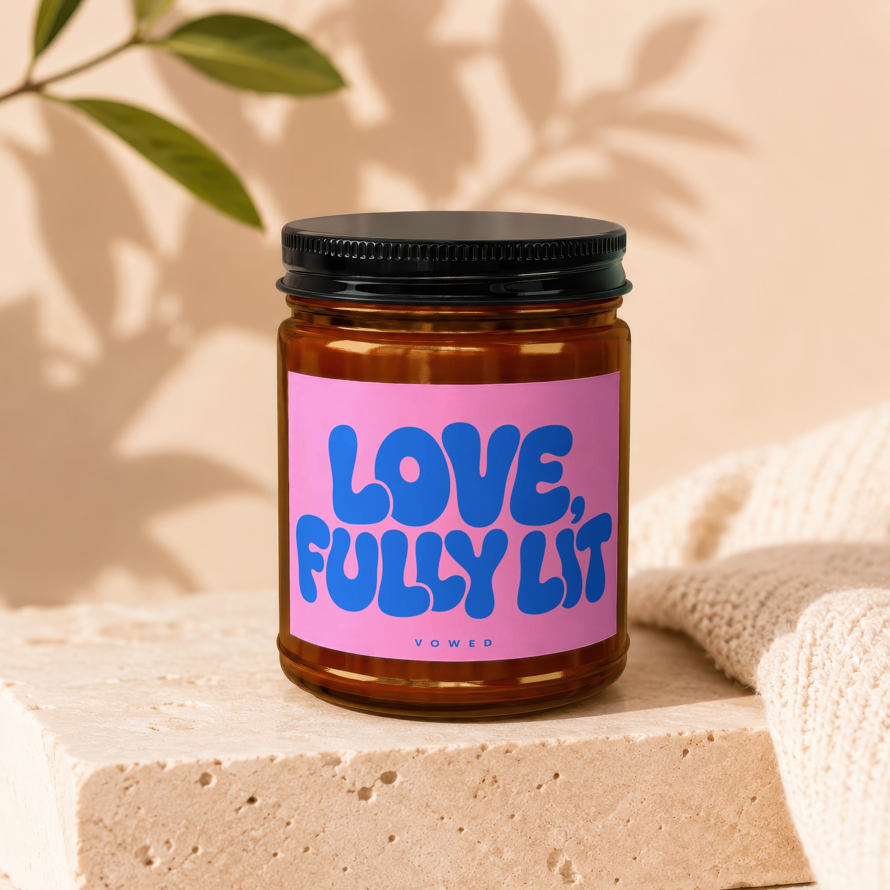 Amber jar candle with pink label reading "LOVE, FULLY LIT" and "VOWED".