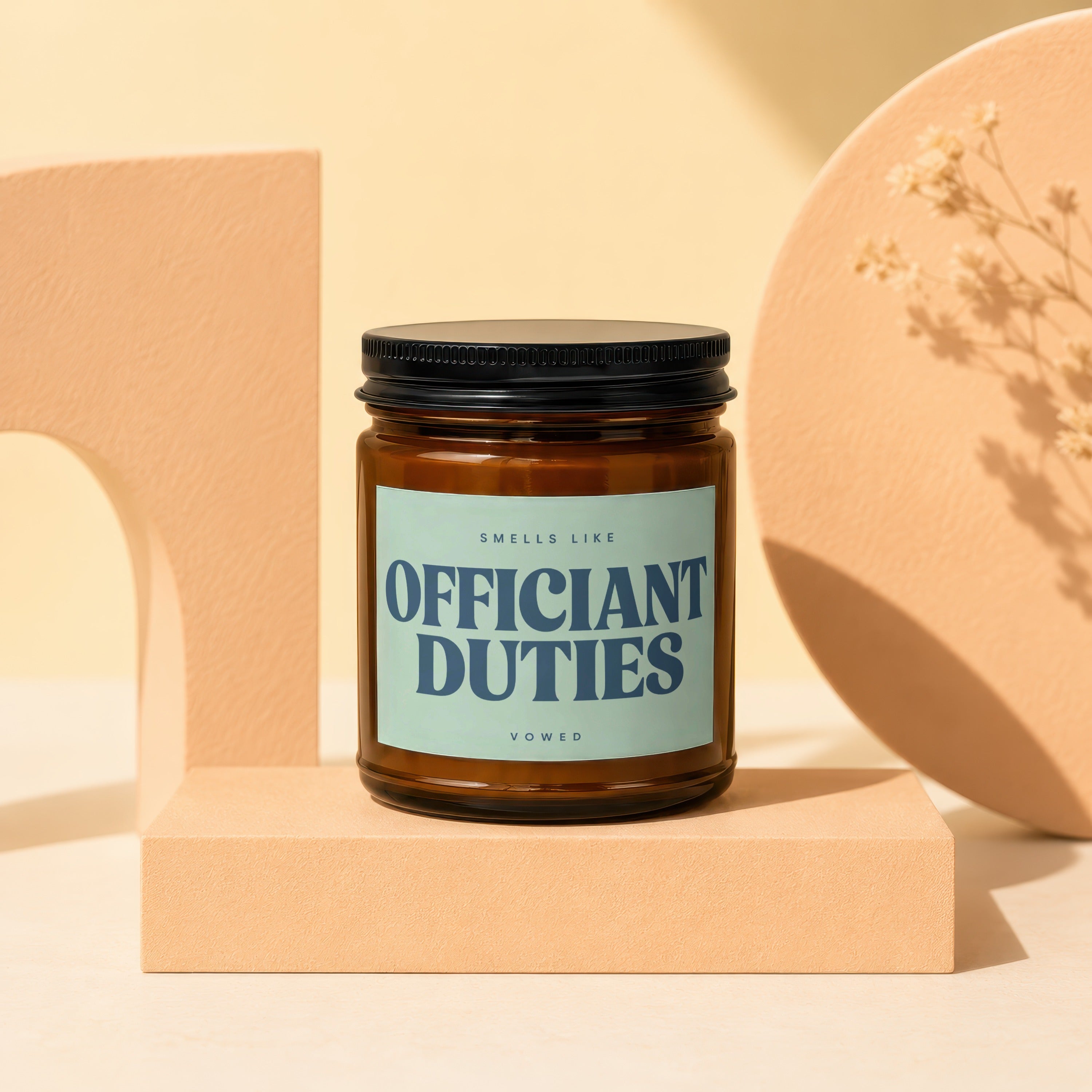 Amber glass candle with light blue label reading "OFFICIANT DUTIES VOWED."