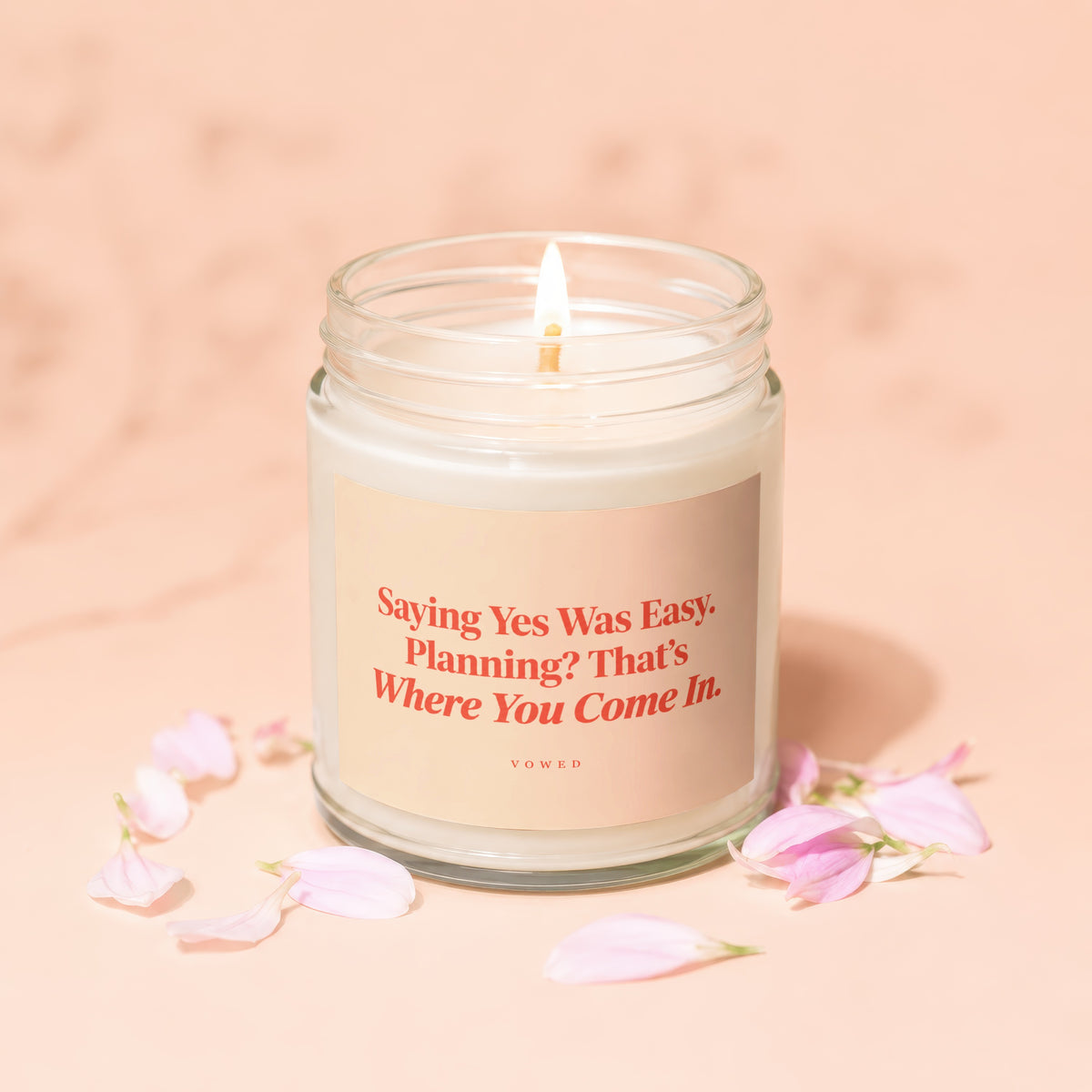 Lit candle with pink petals around it and text: "Saying Yes Was Easy. Planning? That's Where You Come In."