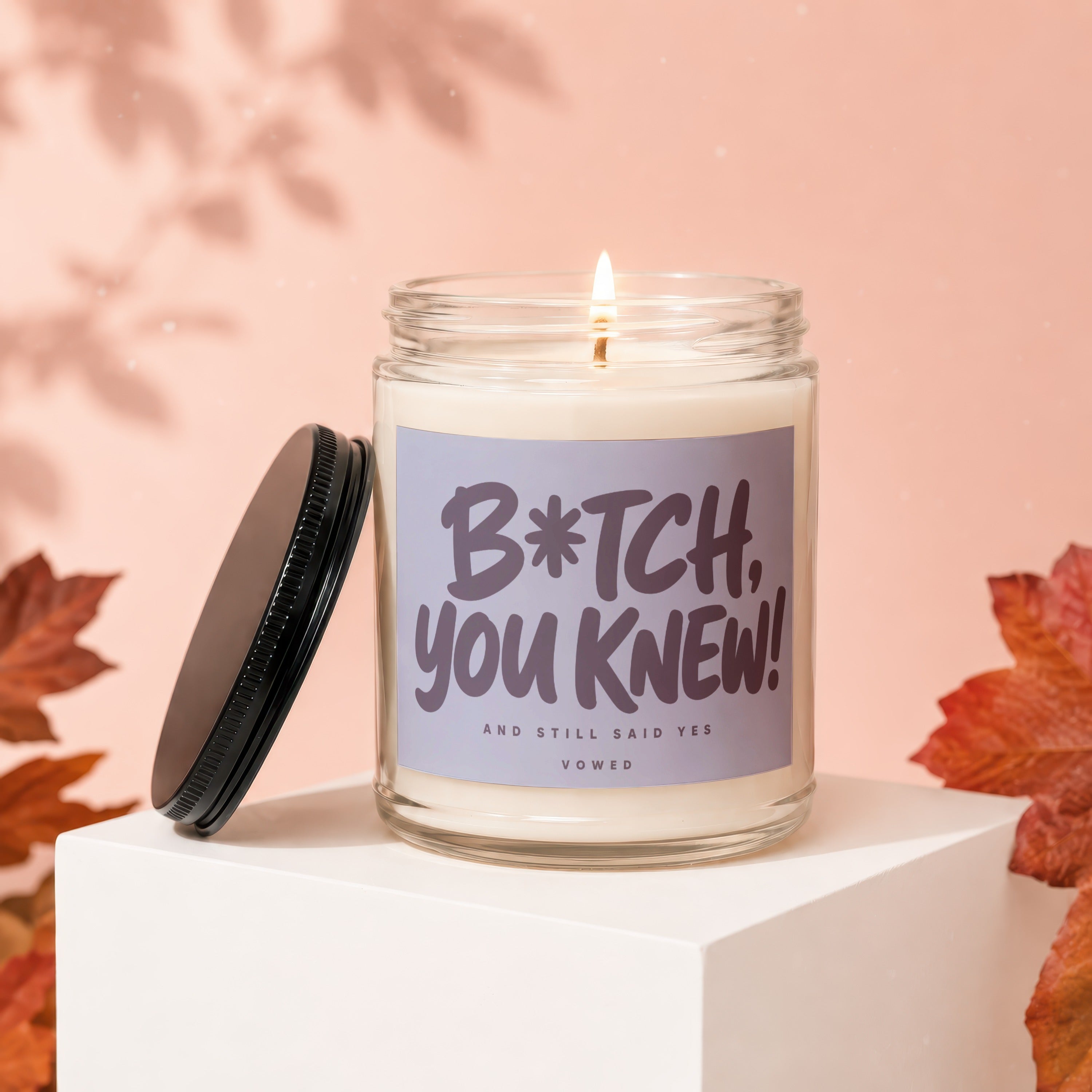 Glass candle with "B*tch, You Knew!" text and lid nearby.