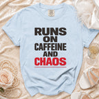 Light blue t-shirt with black and red text reading "RUNS ON CAFFEINE AND CHAOS".