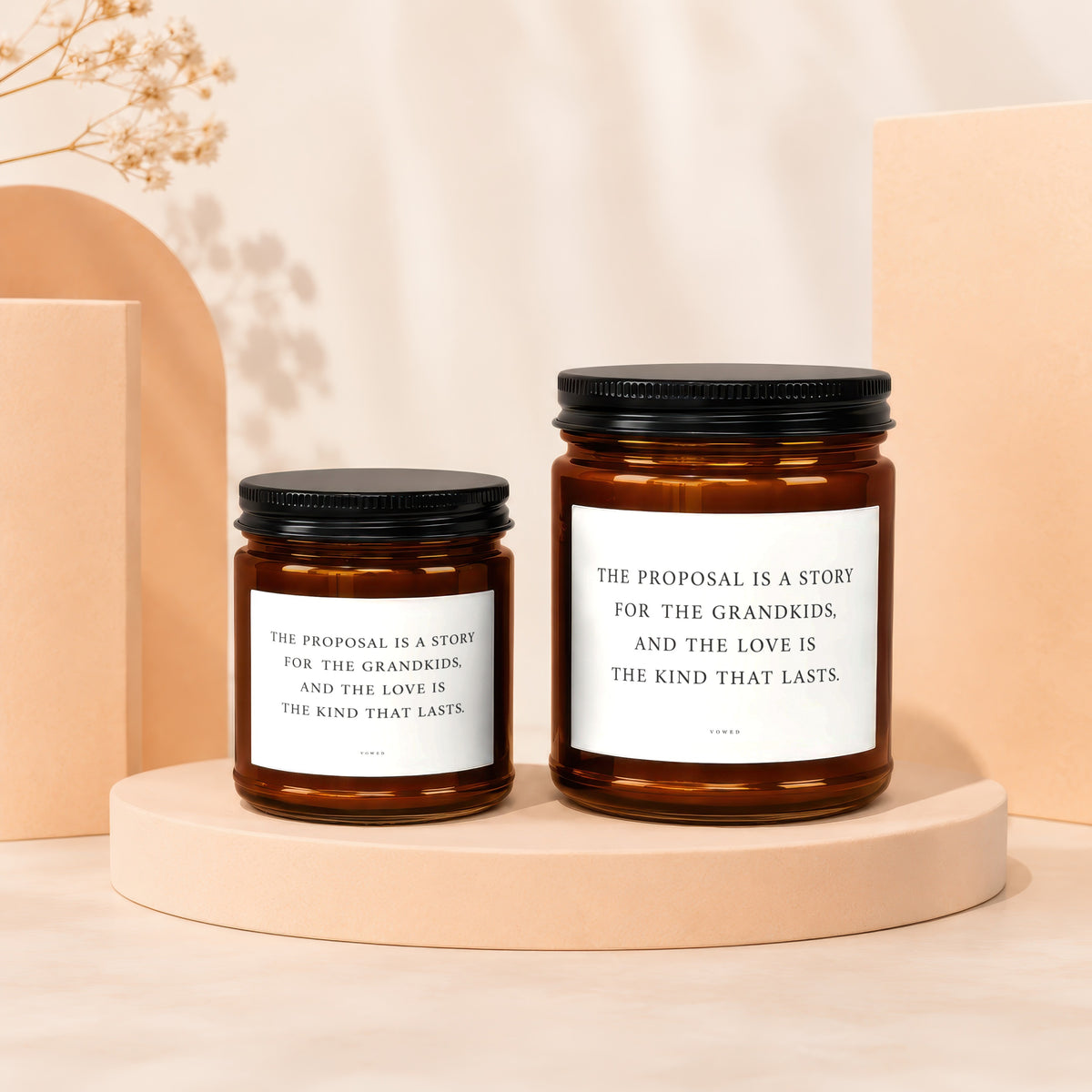 Two amber glass candles with black lids and white labels featuring text.