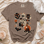 Brown t-shirt with Halloween-themed graphics including cats, skeletons, and a haunted house.